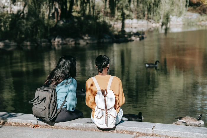 women sitting next to pond